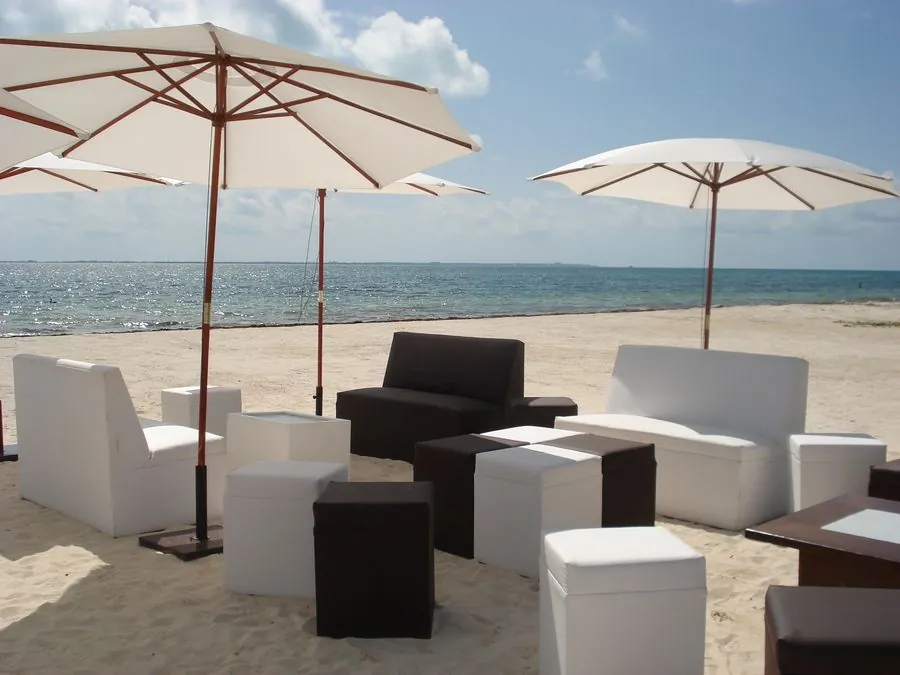 Salas lounge blancas y negras con sombrillas en la playa