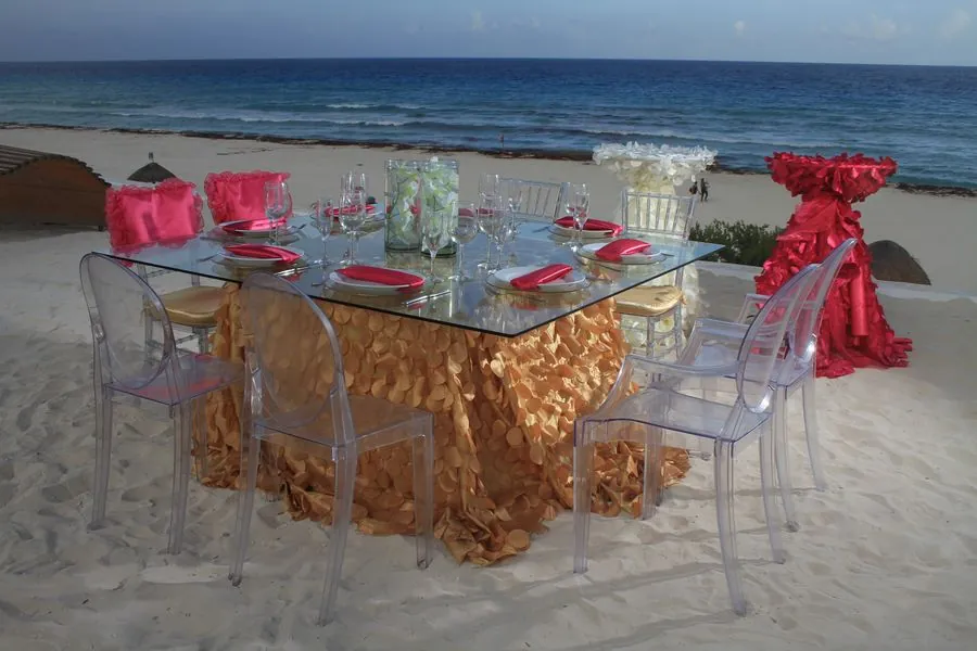 Mesa de vidrio en la playa con sillas Ghost transparentes